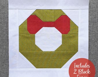 Op de afbeelding: Een groen en rood patchwork quiltblok in de vorm van een krans. De krans is gemaakt van vierkanten en rechthoeken. De tekst "Includes 2 Block Sizes" is zichtbaar in de rechterbenedenhoek van de afbeelding.