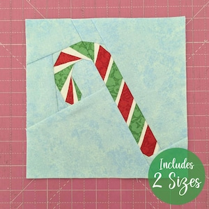 May include: A light blue fabric square with a candy cane design. The candy cane features red and white stripes with green and white accents. The text "Includes 2 Sizes" is in a green circle.