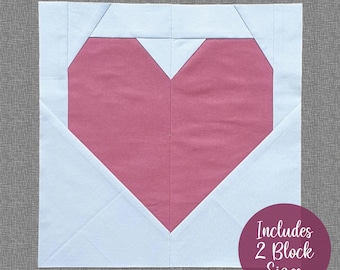 May include: A pink heart-shaped fabric block with white fabric surrounding it. The text "Includes 2 Block Sizes" is in a circle on the bottom right corner of the image.