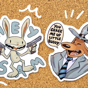 Può includere: Due adesivi di cartoni animati, uno con un coniglio bianco che tiene due pistole con il testo "Hey Sam" e l'altro con un cane marrone che indossa un cappello e un vestito con il testo "You crack me up little buddy".