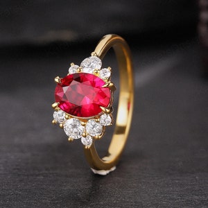 May include: A gold ring with a large oval-shaped ruby gemstone surrounded by smaller round white gemstones.