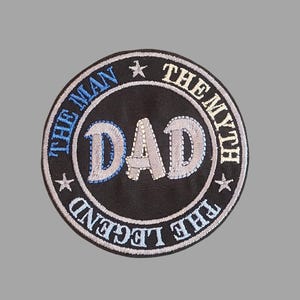 May include: Embroidered patch with the text "DAD" in the center, surrounded by the words "THE MAN THE MYTH THE LEGEND". The patch is circular, with a black background and blue and white stitching.