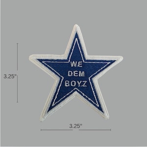 May include: A blue star-shaped patch with white stitching and the words "WE DEM BOYZ". The patch measures 3.25 inches in width and height. The patch has a white border and is on a gray background.