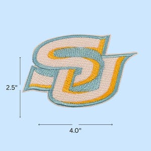 May include: Embroidered patch featuring the letters "SU" in a stylized design. The patch is approximately 4.0 inches wide and 2.5 inches tall. The design incorporates light blue, yellow, and off-white colors, with a light blue background.