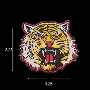 May include: Embroidered tiger patch, measuring 3.25 inches in height and width. The patch features a detailed tiger head with yellow, black, red, and white thread. The tiger is snarling, with its mouth open, revealing teeth and a red tongue.