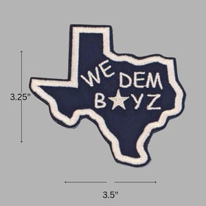 May include: Embroidered patch in the shape of Texas, navy blue with white trim. The patch measures 3.5 inches wide and 3.25 inches tall. The text "WE DEM BAYZ" is embroidered in white, with a white star replacing the letter "A".