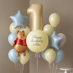 Puede incluir: Un festivo ramo de globos para un primer cumpleaños. Incluye un gran globo con el número uno, globos en forma de estrella y globos redondos en colores pastel. También se incluye un globo de Winnie the Pooh y un globo con la frase "Happy Birthday Alex".