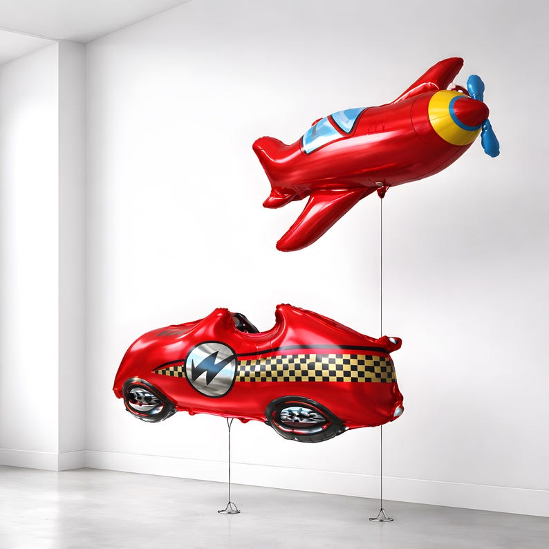 May include: Two red foil balloons: a race car with a lightning bolt emblem and a checkered flag design, and an airplane with blue and yellow accents. Both are suspended by strings, perfect for a party or celebration.
