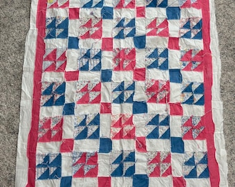Parte superior de una colcha vintage hecha a mano con un diseño de variación de molinillo en azul y rosa.