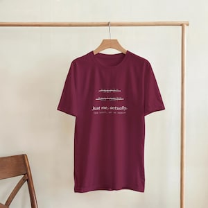 Può includere: Una t-shirt a maniche corte color bordeaux con testo bianco stampato sul davanti che recita "sir?" e "ma'am?" con linee orizzontali che li attraversano, seguito dal testo "just me, actually." e "your script, not my problem.".