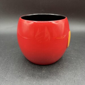 Pu&ograve; includere: Una tazza in ceramica rossa, arrotondata, con interno nero. Un piccolo accento circolare giallo &egrave; sul lato. La tazza ha una finitura liscia e lucida e un design semplice. Adatta per bevande calde o fredde. Altezza circa 10 cm.