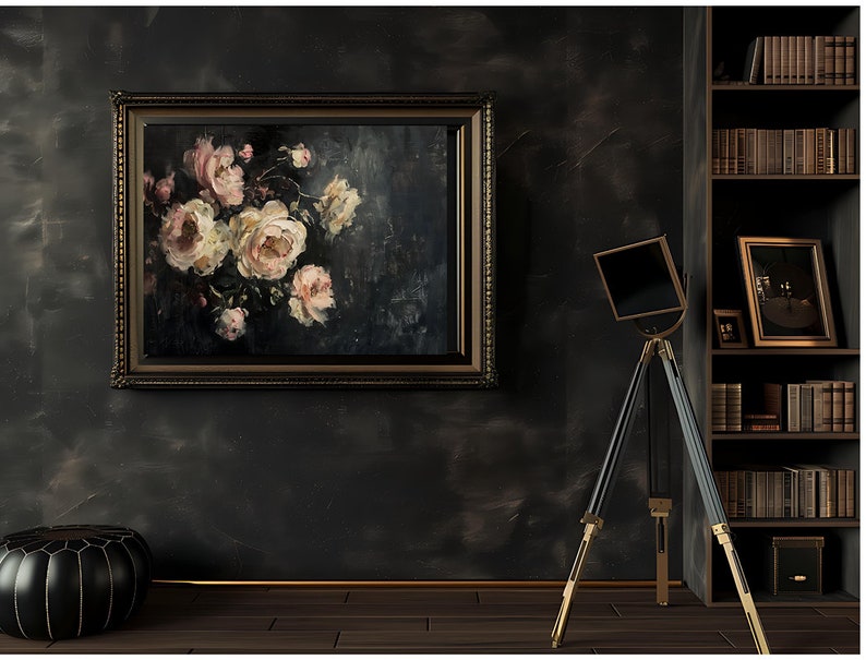 May include: An oil painting of pink and white roses in a dark, ornate frame hangs on a dark gray wall. A black and gold tripod stand with a square top is in front of the wall. A black leather ottoman sits on the wooden floor.