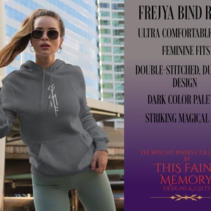 May include: A gray hooded sweatshirt with a white embroidered Frejya bind rune. The text "The Witchy Wares Collection by This Faint Memory Designs & Gifts" is printed on the bottom of the image.
