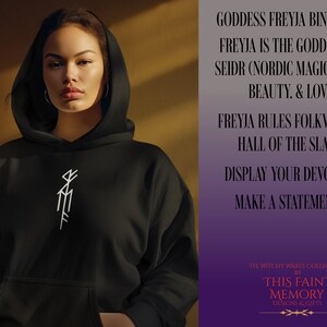 May include: Black hooded sweatshirt with a white bind rune symbol on the front. The text on the right side of the image reads "Goddess Freyja Bind Rune, Freyja is the Goddess of Seidr (Nordic Magic), War, Beauty, & Love, Freyja Rules Folkvangr, Hall of the Slain, Display Your Devotion, Make a Statement, The Witchy Wares Collection by This Faint Memory Designs & Gifts."