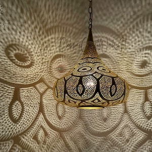 May include: A gold Moroccan pendant light with intricate cut-out designs. The light casts a beautiful pattern on the wall.