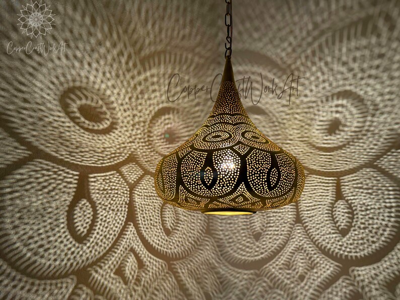 May include: A gold Moroccan pendant light with intricate cut-out designs. The light casts a beautiful pattern on the wall.