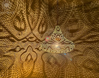 May include: A gold metal pendant light fixture with a geometric pattern casts a decorative shadow on the ceiling. The light fixture is hanging from a chain.
