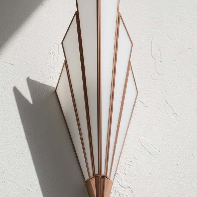 May include: A wall sconce featuring a fan-shaped design with white frosted glass panels framed in metallic copper. The fixture has a vertical, symmetrical structure with multiple segments that taper toward the bottom, creating a geometric appearance.