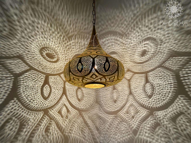 May include: A gold Moroccan pendant light with intricate cut-out designs casts a patterned shadow on the ceiling.