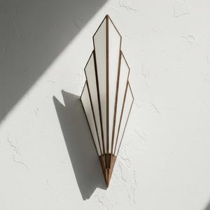 May include: A wall sconce featuring a fan-shaped design with five white glass panels framed in metallic bronze. The fixture tapers to a pointed bronze base at the bottom, creating a geometric silhouette that extends vertically against the wall surface.