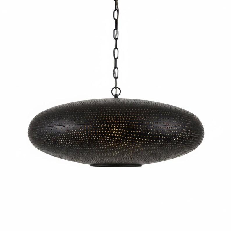 May include: A black, disc-shaped pendant light fixture featuring a textured surface with numerous small, perforated holes. The lamp is suspended from a matching black metal chain, creating a focused downward light through the intricate pattern.