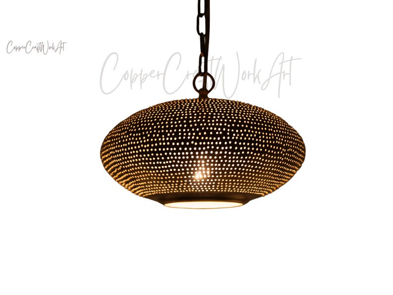 May include: A dark brown, oval-shaped pendant light fixture featuring a dense pattern of small, circular perforations across its surface. The lamp hangs from a dark metal chain and emits a warm, focused light from its open bottom aperture.