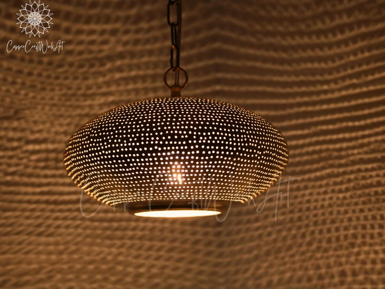 May include: A dome-shaped pendant light fixture crafted from metallic material with a perforated surface pattern. The lamp features a warm, glowing light emitting from the bottom opening and through the small holes, suspended by a metal chain.