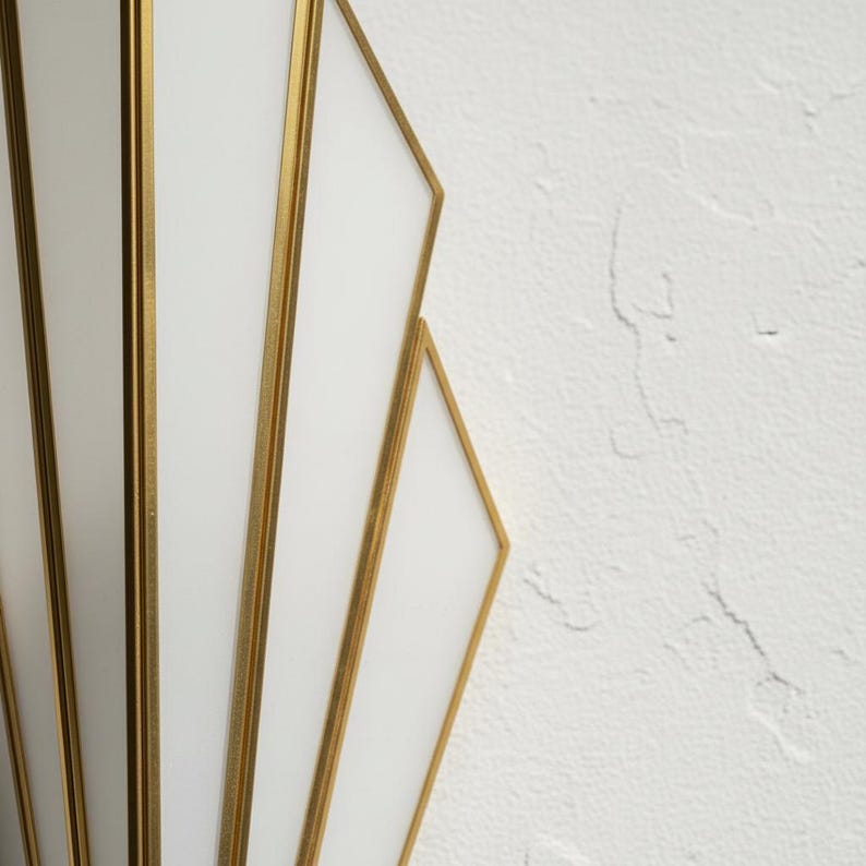 May include: A wall sconce featuring a series of white glass panels framed in thin gold metal strips. The design consists of multiple vertical and angled segments arranged in a fan-like pattern, creating a geometric structure with clean lines.