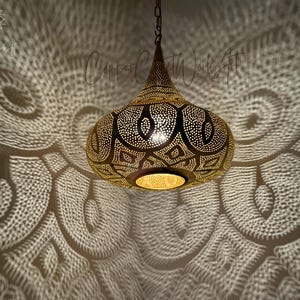 May include: A gold Moroccan pendant light with intricate cut-out designs casts a patterned shadow on the ceiling.