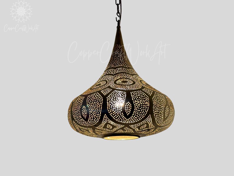 May include: A black metal pendant light with a teardrop shape and intricate cut-out design. The light has a gold finish and is perfect for adding a touch of Moroccan style to any room.