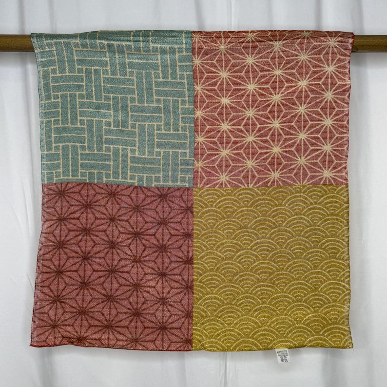 May include: A square textile divided into four sections, each with a different pattern. The top left has a blue and beige woven design, the top right and bottom left have a red starburst pattern, and the bottom right has a gold wave pattern.