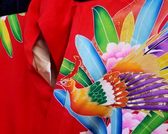 Könnte beinhalten: Ein roter Kimono mit einem bunten Phönix und floralem Design. Der Phönix ist mit goldenen, violetten und grünen Akzenten dargestellt. Der Kimono ist aus einem weichen, seidenartigen Stoff gefertigt.