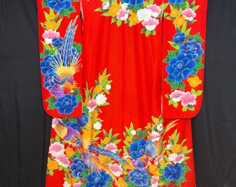 Può includere: Un kimono rosso con un motivo floreale con pavoni blu e gialli, fiori rosa e bianchi e foglie verdi.