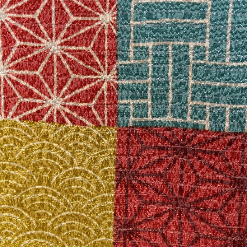 May include: A close-up of a textile with four distinct patterned quadrants. The top left and bottom right quadrants feature red geometric starburst designs with white accents. The top right quadrant has a teal grid pattern, and the bottom left has a gold wave pattern.