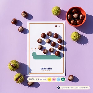Könnte beinhalten: Eine weiße rechteckige Karte mit einer grünen Schneckenillustration, deren Gehäuse aus zwölf braunen Kastanien besteht. Die Karte zeigt den Text "Schnecke", "x 12" und "PDF in 4 Sprachen DE EN FR ES". Lose Kastanien und stachelige grüne Hüllen liegen um die Karte herum.