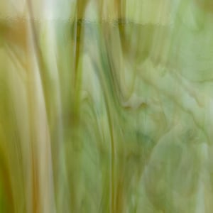 May include: A sheet of green and yellow iridescent glass with a swirled pattern. The glass is translucent and has a slight shimmer.