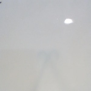 May include: A white, rectangular, glossy surface with two black star-shaped objects on a white surface. The surface has a label that reads "214-5-74"