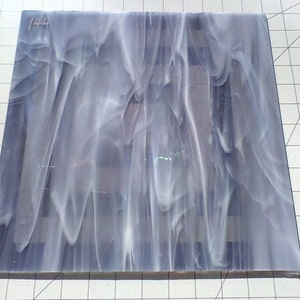 May include: A sheet of white and gray marbled glass with a swirling pattern. The glass is translucent and has a slight shimmer.