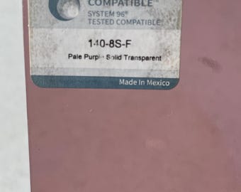 May include: A close-up of a pale purple, solid, transparent glass sheet. The sheet has a sticker in the upper left corner with the text "OCEANSIDE COMPATIBLE" and "SYSTEM 96 TESTED COMPATIBLE". The sticker also includes the text "140-8S-F" and "Made In Mexico".