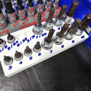 May include: A set of three ceramic mugs with a speckled, matte finish. The mugs are in shades of cream, light gray, and dark gray. Each mug has a simple, minimalist design and a rounded handle.