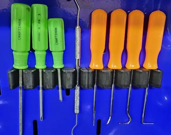 May include: A set of tools mounted on a blue surface, including three green Craftsman screwdrivers, a central metal pick tool with a textured handle, and four orange-handled precision picks with various angled metal tips.