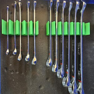 May include: A white ceramic mug with a black handle and the text "But First, Coffee" in a black, handwritten-style font. The mug is on a white surface.