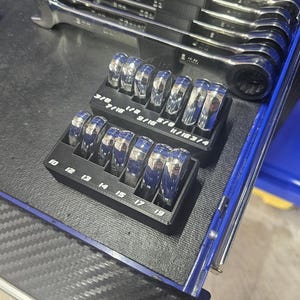 May include: Two black plastic wrench organizers holding chrome wrenches. The top row features imperial sizes 3/8, 7/16, 1/2, 9/16, 5/8, 11/16, and 3/4 inches. The bottom row features metric sizes 10, 12, 13, 14, 15, 17, and 19 millimeters.