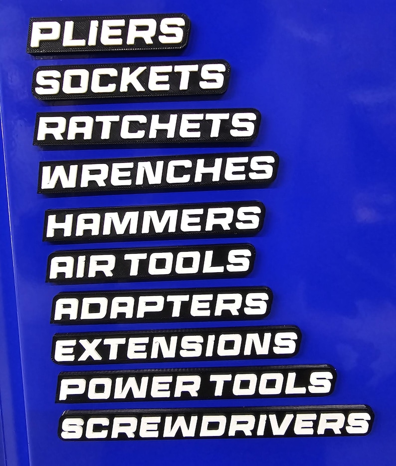 May include: Black and white tool labels with the following text: PLIERS, SOCKETS, RATCHETS, WRENCHES, HAMMERS, AIR TOOLS, ADAPTERS, EXTENSIONS, POWER TOOLS, and SCREWDRIVERS. The labels are on a blue surface.