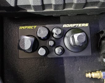 May include: A black rectangular organiser tray containing six metal impact adapters of varying sizes. The tray features the yellow text IMPACT ADAPTERS printed across the top. The adapters are arranged in a specific layout within the moulded slots.