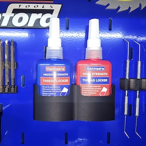 May include: Two bottles of Hannaera Thread Locker, one blue and one red, displayed on a blue background. The blue bottle is labeled "Medium Strength," and the red bottle is labeled "High Strength." Both bottles are in a black holder.