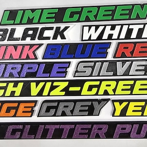 May include: A collection of rectangular signs in various colors, each displaying a different color name in bold, sans-serif font. Colors include lime green, black, white, pink, blue, red, purple, silver, high viz-green, orange, grey, yellow, and dark glitter purple.