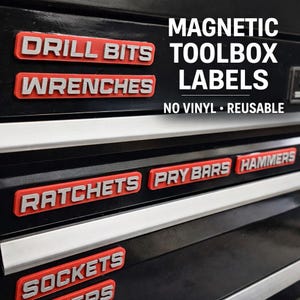 May include: Magnetic toolbox labels in red and white, with text including "DRILL BITS", "WRENCHES", "RATCHETS", "PRY BARS", "HAMMERS", and "SOCKETS". The labels are displayed on a black toolbox. The text "MAGNETIC TOOLBOX LABELS" is also visible.