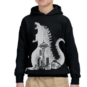 May include: Black hooded sweatshirt featuring a white graphic print of a Godzilla-like monster standing in front of the Seattle Space Needle and skyline.