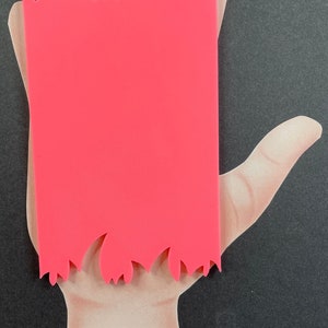 May include: A bright pink rectangular object with a flame-like edge is positioned over a hand illustration. The hand is depicted with a light skin tone against a black background. The object's color is a vibrant, solid pink.